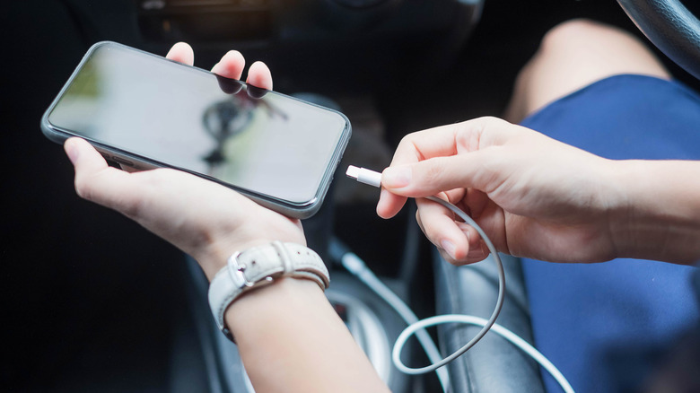 человек подключает свой телефон к автомобилю с помощью USB-кабеля для зарядки и Android Auto