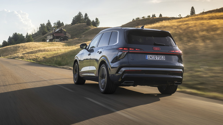 Новый Audi Q7 в движении по проселочной дороге, вид сзади в 3/4