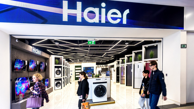 Люди идут перед магазином бытовой техники Haier.