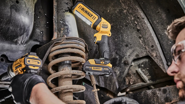 Ручной светодиодный фонарь DeWalt 20V MAX*, используемый работником для освещения работы.
