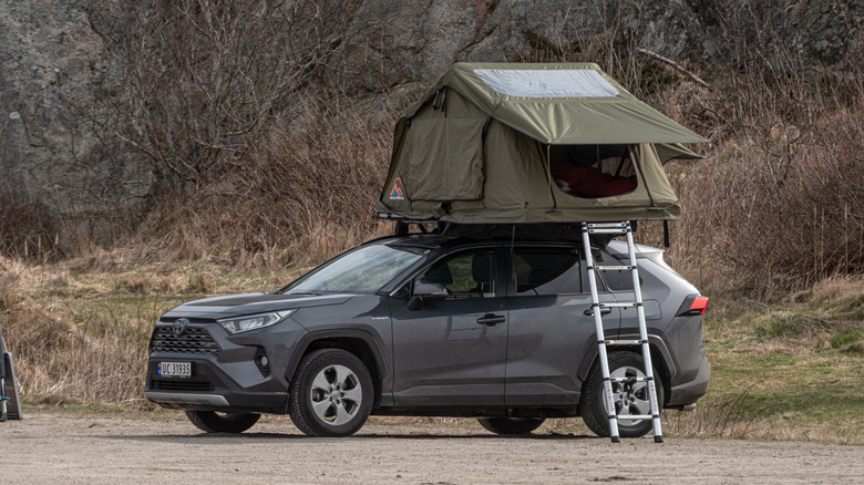 Вид сбоку на серую Toyota RAV4 с палаткой на крыше.