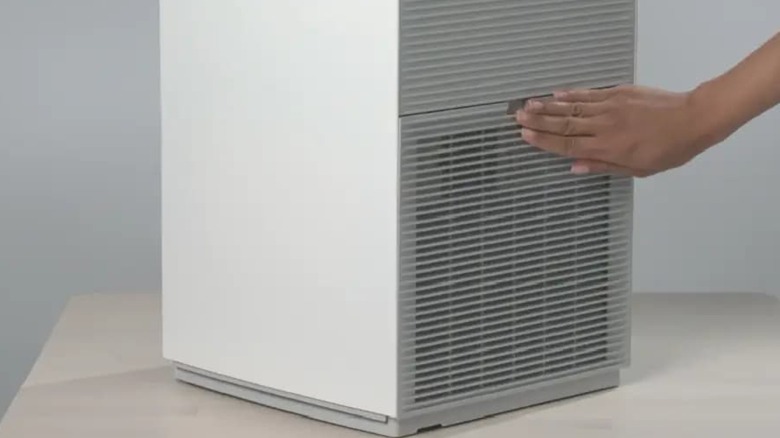 Человек касается вентиляционного отверстия очистителя воздуха Daikin.