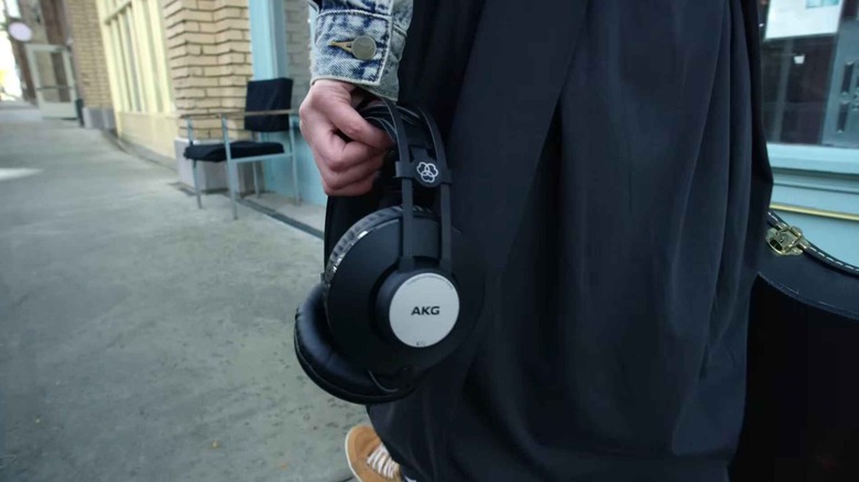Крупный план женщины, идущей по тротуару с наушниками AKG K72.