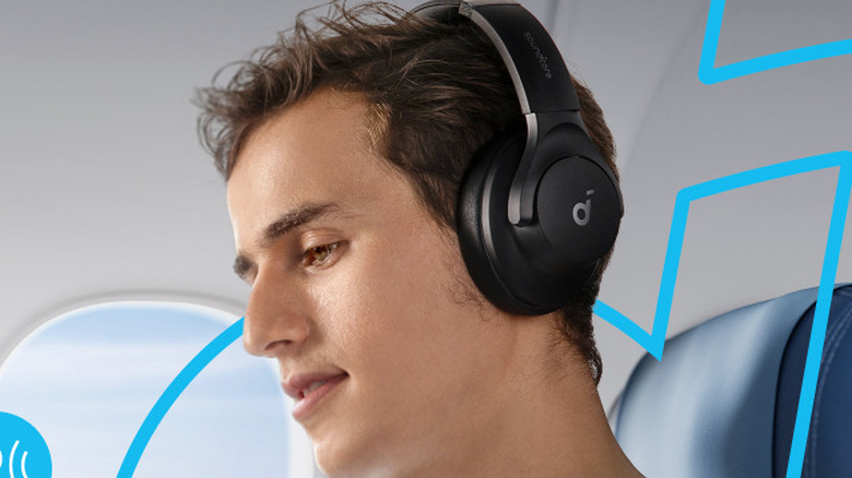 Крупный план человека, сидящего в кресле самолета в наушниках Anker Soundcore Q20i.