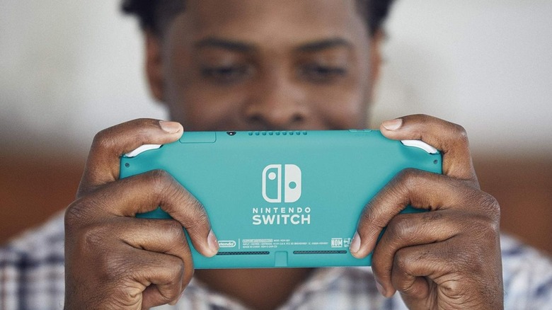 Мужчина держит бирюзовый Nintendo Switch Lite