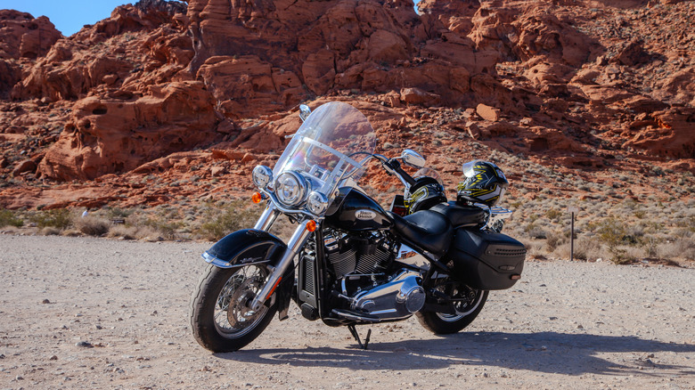 Мотоцикл Harley-Davidson припаркован в пустыне на фоне красных скалистых гор.