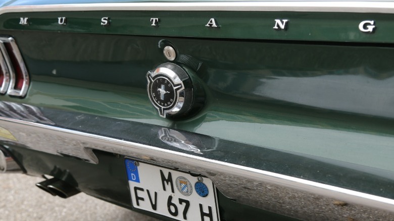 Крупный план логотипа и названия Mustang на задней части зеленого Ford Mustang 1967 года выпуска.