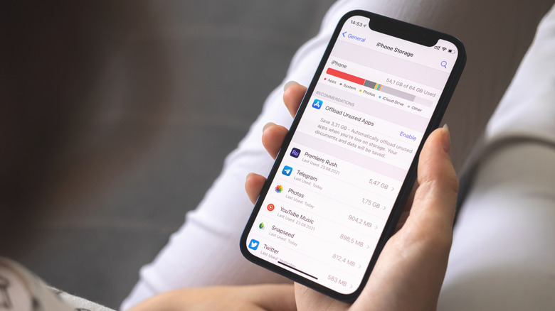 Человек с iPhone с открытым разделом «Память» в настройках.