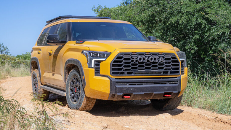 Желтая Toyota Sequoia TRD Pro 2027 года выпуска едет по грунтовой дороге