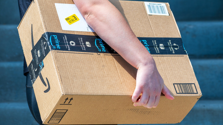 Кто-то несет большую коробку Amazon.