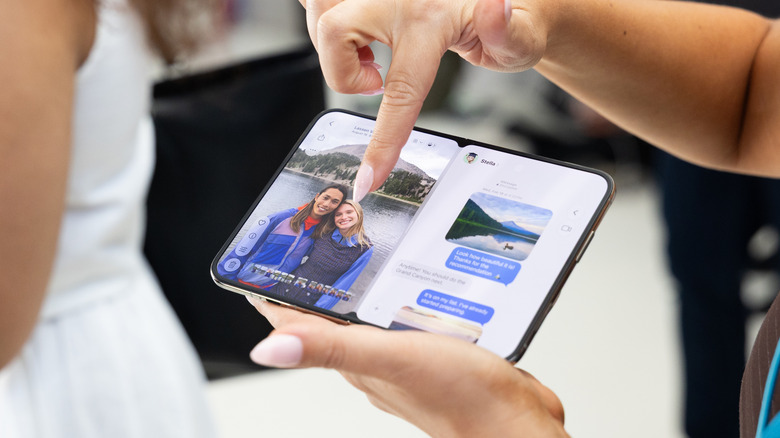 Женщина держит открытый телефон iPhone Duo