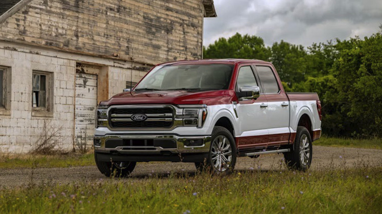 Ford F-150 2027 года в двухцветной окраске припаркован на сельской грунтовой дороге перед ветхим зданием