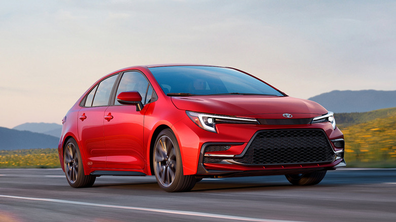 Красная Toyota Corolla 2027 года выпуска на сельской дороге