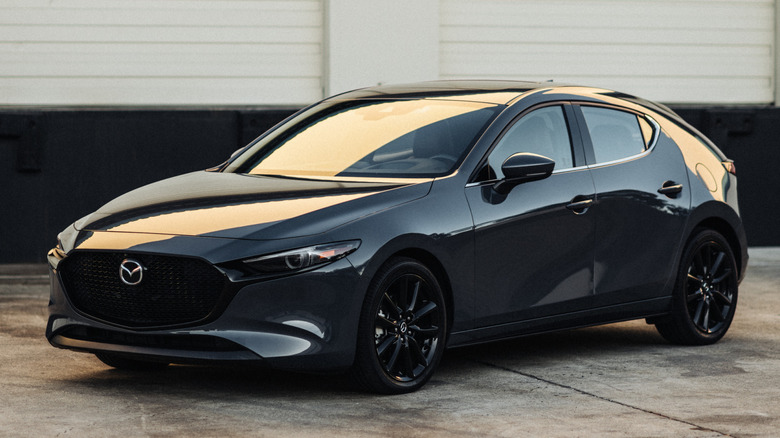 Черная Mazda3 2026 года, припаркованная на бетоне в условиях слабого освещения