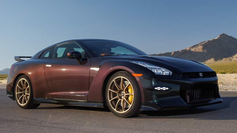 Nissan GT-R R35 цвета Midnight Purple, припаркованный на гоночной трассе, вид спереди справа в 3/4