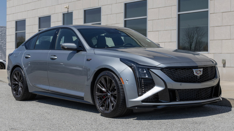 Вид спереди в 3/4 на серебристый Cadillac CT5-V Blackwing, припаркованный перед зданием.