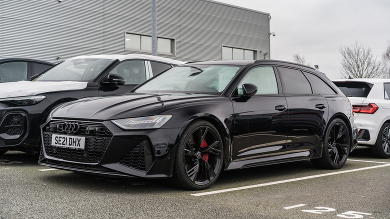 Черный Audi RS6 Performance Avant, припаркованный рядом с другими автомобилями Audi.