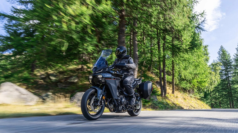 Человек на туристическом мотоцикле Yamaha в лесистой местности.