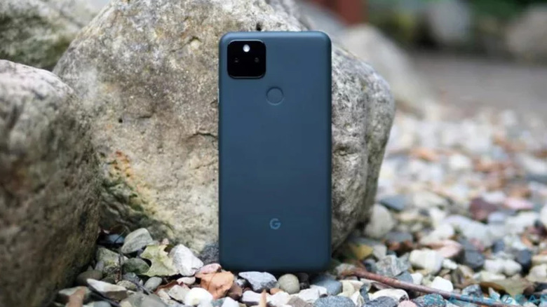 Google Pixel 5a стоит вертикально на небольших камнях