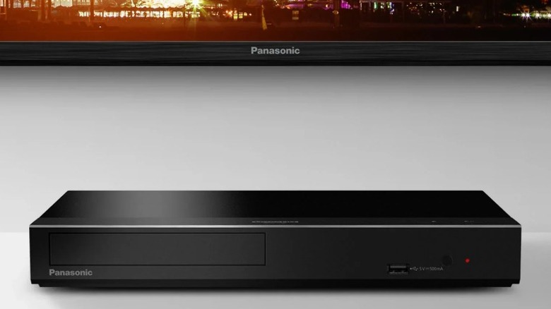 Blu-ray-плеер Panasonic DP-UB450P-K на белой полке под телевизором Panasonic