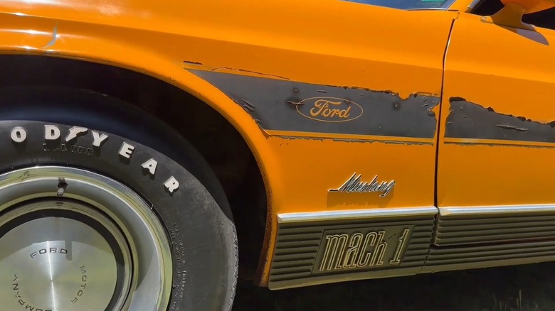 Крупным планом Mustang Mach 1 Twister Special 1970 года выпуска: передняя левая боковая панель с отслаивающимися наклейками и 