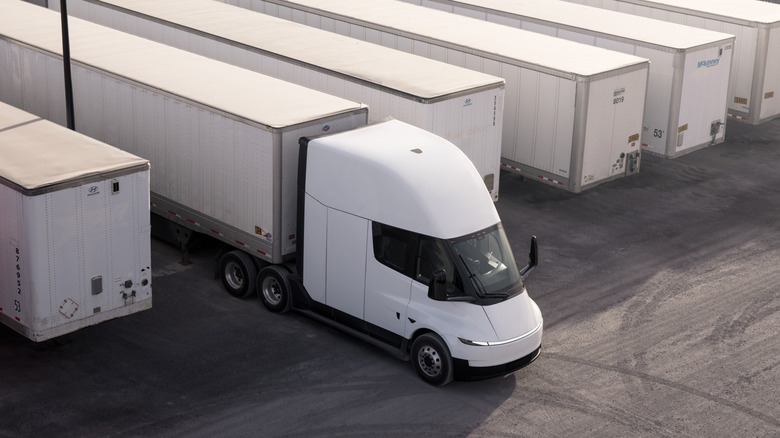 Вид сверху на белый полуприцеп Tesla Semi, тянущий прицеп на грузовой базе.