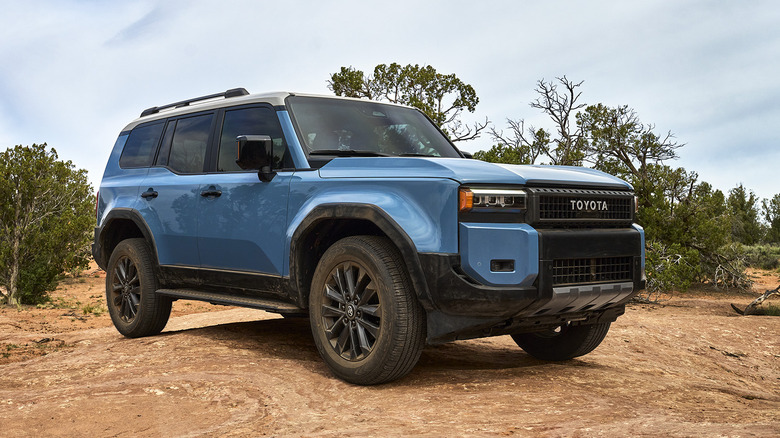 Вид спереди 3/4 синего Toyota Land Cruiser на пустынной тропе.