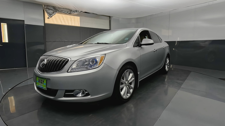 Серебристый Buick Verano 2014 в автосалоне, вид спереди 3/4