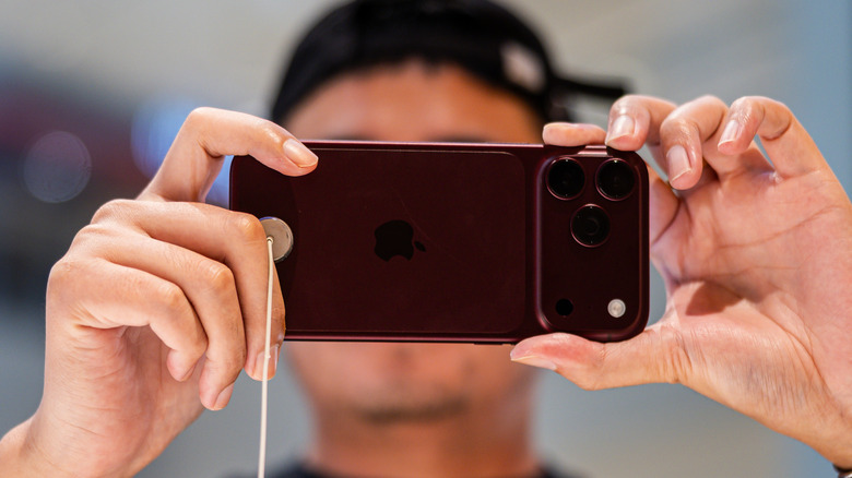 Человек держит iPhone 18 Pro, чтобы сделать снимок.