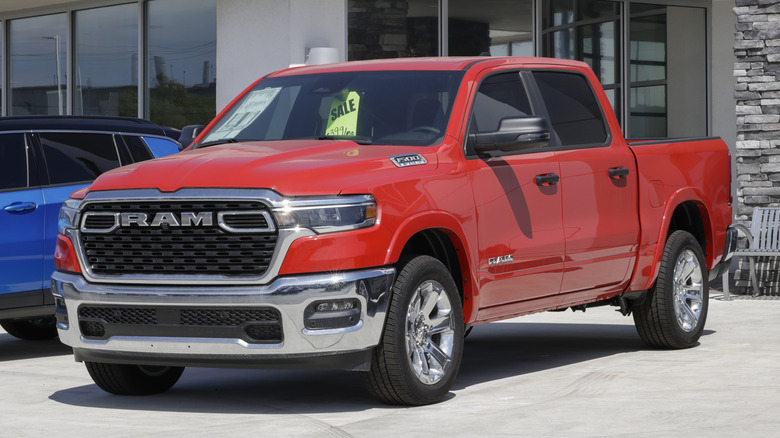 Красно-хромированный Ram 1500, припаркованный перед автосалоном.