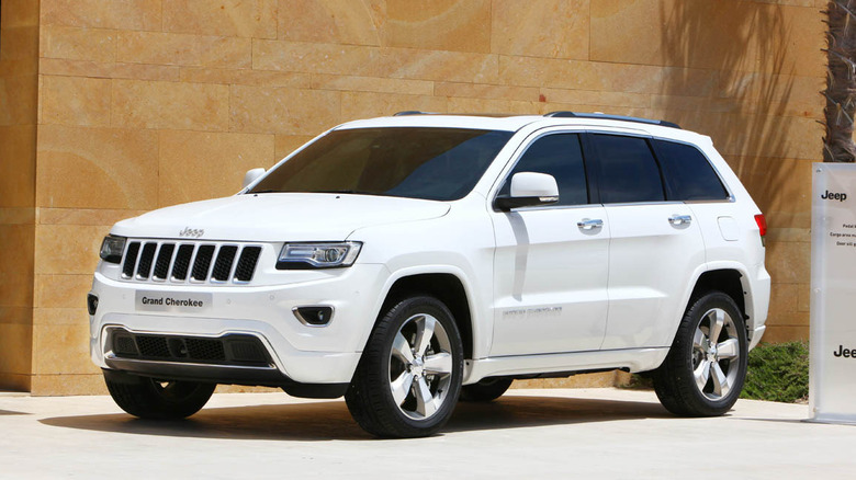 Белый Jeep Grand Cherokee WK2 в базовой комплектации на промо-мероприятии, вид спереди 3/4