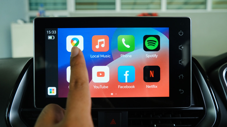 Крупный план: палец выбирает значок Google Maps в интерфейсе Android Auto.