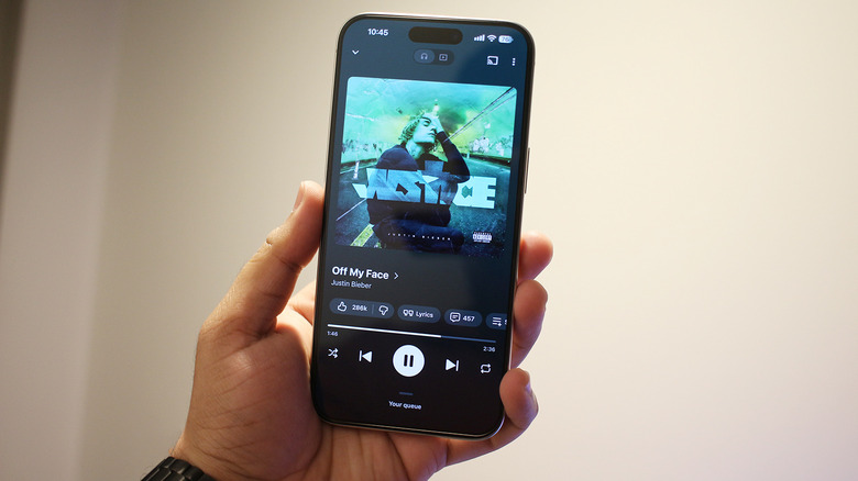 Рука держит iPhone со Spotify на экране