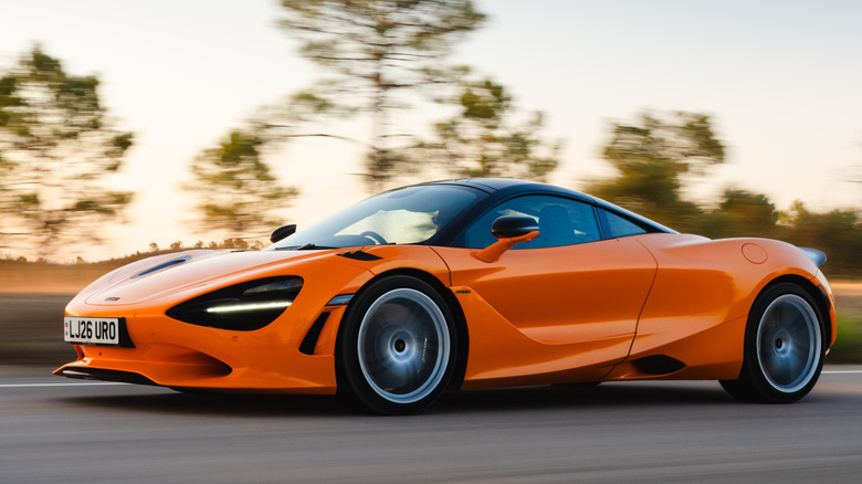 Вид спереди в 3/4 на McLaren 750S, едущий по дороге в лесной местности