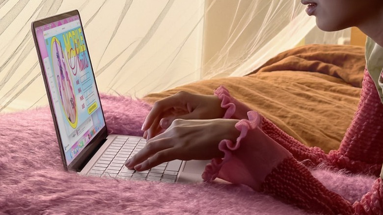 Руки печатают на MacBook Neo на кровати
