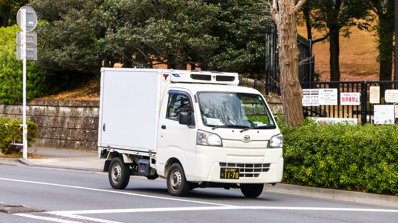 Белый рефрижератор Daihatsu HiJet на городской дороге