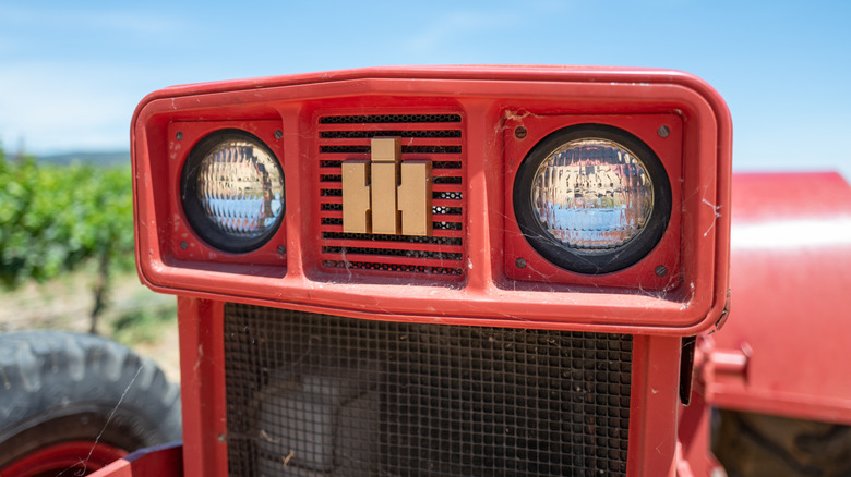 Крупный план передней решетки красного трактора International Harvester с видимым логотипом.
