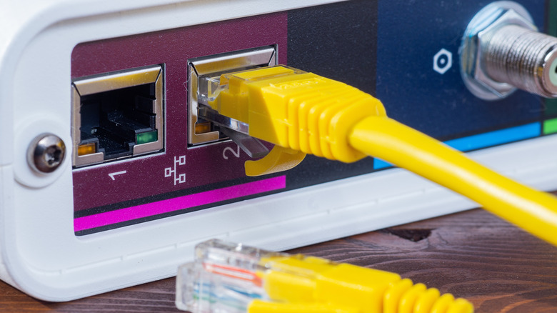 Желтый кабель Ethernet, подключенный к порту сетевого маршрутизатора крупным планом.