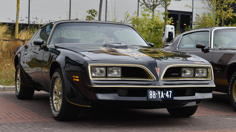 Вид шрифта на черный Pontiac Trans Am второго поколения, припаркованный на автосалоне.