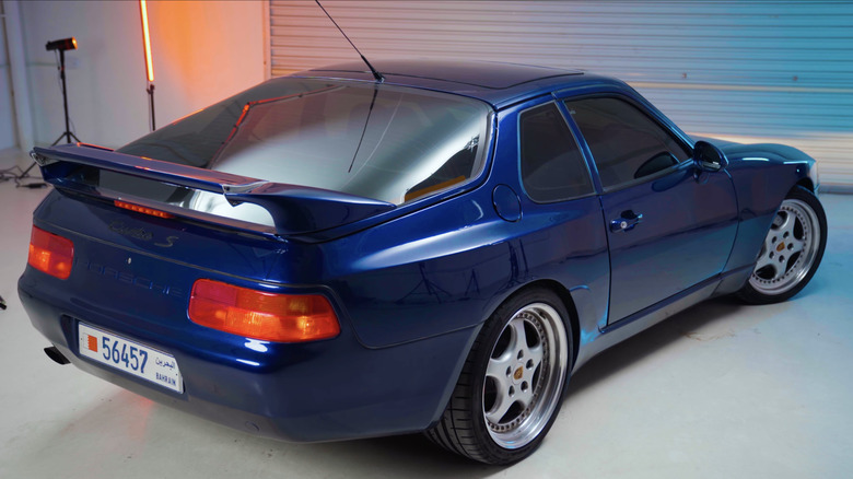 Редкий синий Porsche 968 Turbo S, сфотографированный сзади под студийным освещением в гараже.