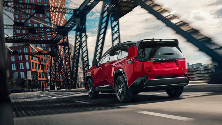 Вид сзади в 3/4 на красную Toyota RAV4 GR Sport, едущую по мосту.