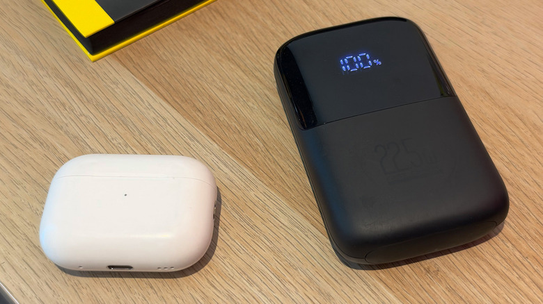 Power Bank рядом с чехлом AirPods на деревянном столе.