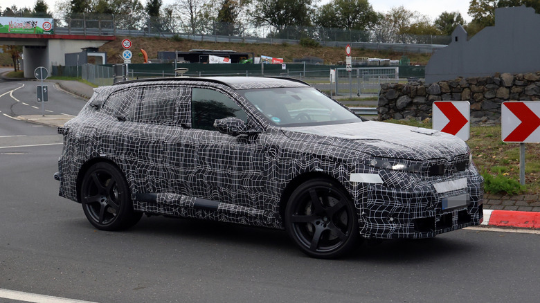 Замаскированный BMW X5 M выезжает за угол.