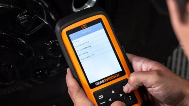Человек, использующий инструмент Gearwrench TPSM в автомобиле.