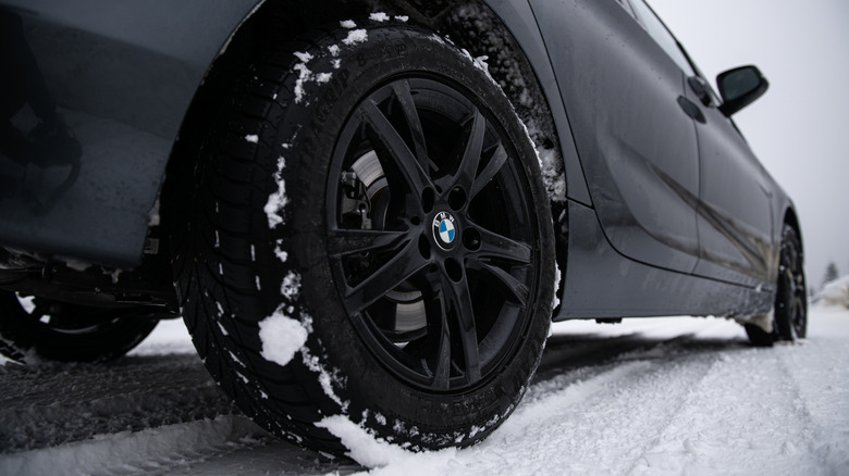 Крупный план темно-серого BMW с шинами Goodyear, едущего по снегу.