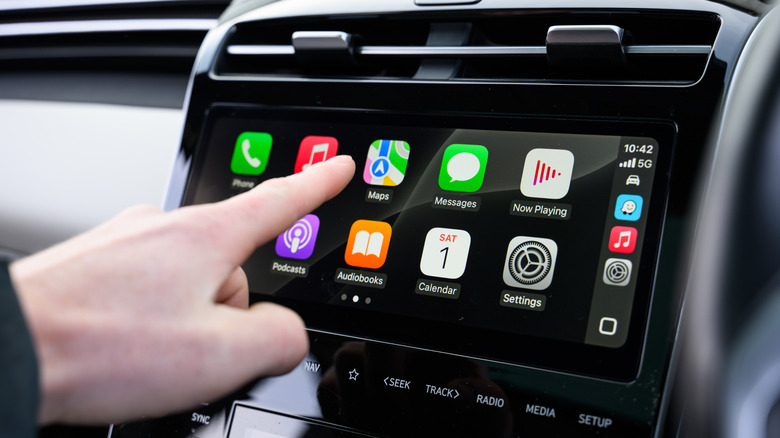 Человек, использующий Apple CarPlay в информационно-развлекательной системе.